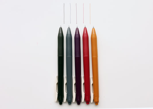 Five slim pens sepia black, dark gray, bordeaux purple, cassis red, and camel yellow, arranged vertically on a plain white background with thin colored tester lines above each pen.