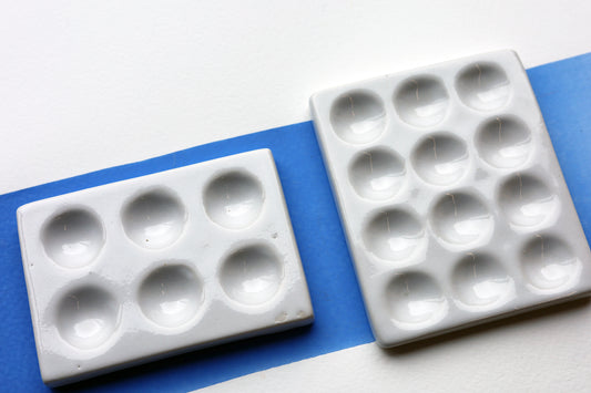 Two White Porcelain spot mixing plates on painted swatch with a white background