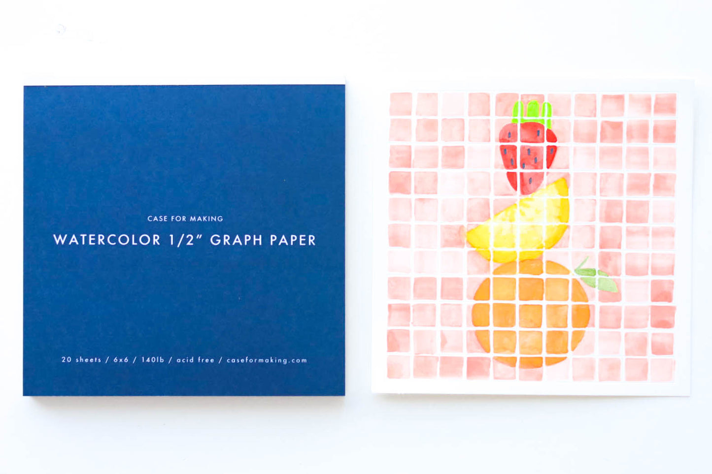 The closed, top-bound 6" x 6" Watercolor 1/2" Graph Paper pad. Showing the dark blue cover with white lettering. Also shown is a painted sample sheet of the 1/2" Graph Paper.
