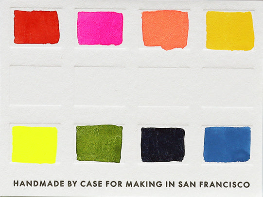 A handmade watercolor palette featuring Case for Making Colors: French Vermilion, CfM Hot Pink, CfM Coral, CfM Oxalis, Fluorescent Yellow 2, CfM Olive, Synthetic Indigo, CfM Shadow Blue painted on a swatch card.