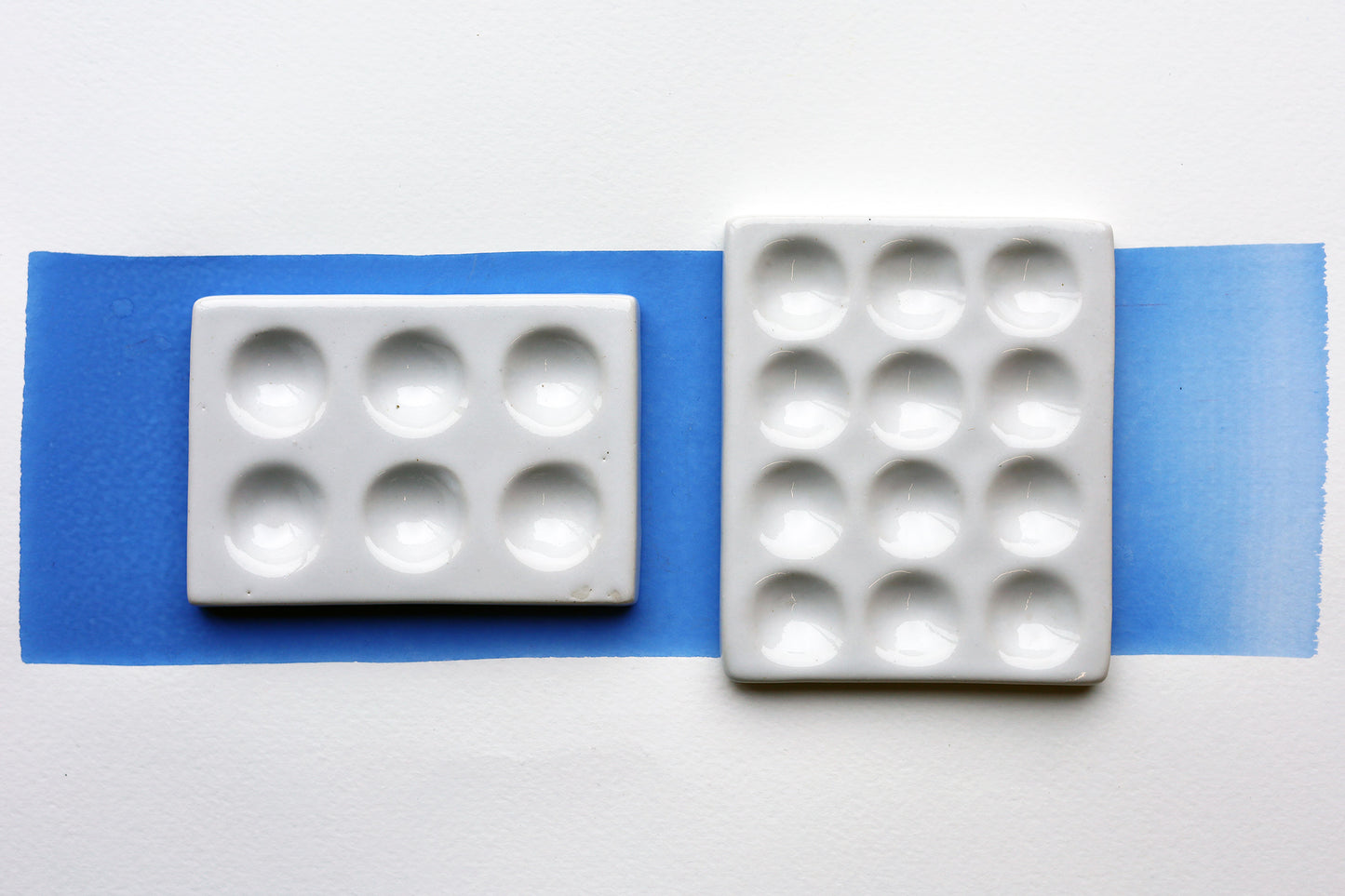 Two White Porcelain spot mixing plates on painted swatch with a white background