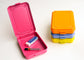 A stack of four rectangular stamped metal storage in bright pink, orange, lilac, and yellow, photographed on a clean white background. One box is open showing an eraser and pack of pencil lead.