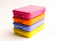A stack of four rectangular stamped metal storage in bright pink, orange, lilac, and yellow, photographed on a clean white background.