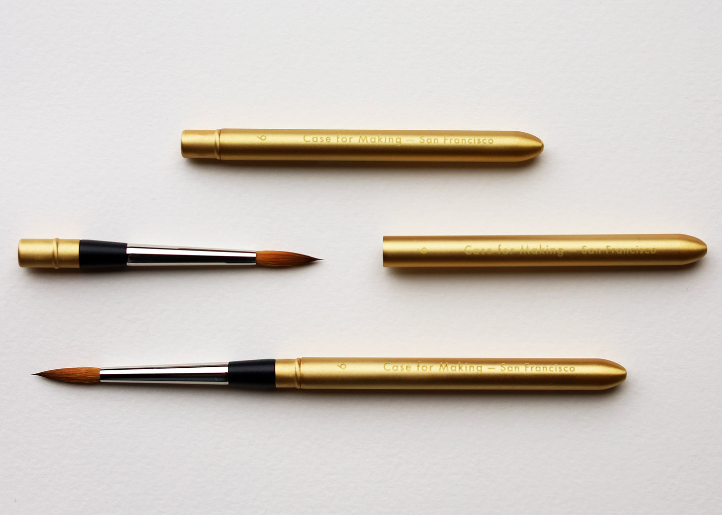 Four gold watercolor brushes and brushes with black ferrules and brown bristles, arranged on a clean white background showing how the brushes folds and closes to protect the brush tip.