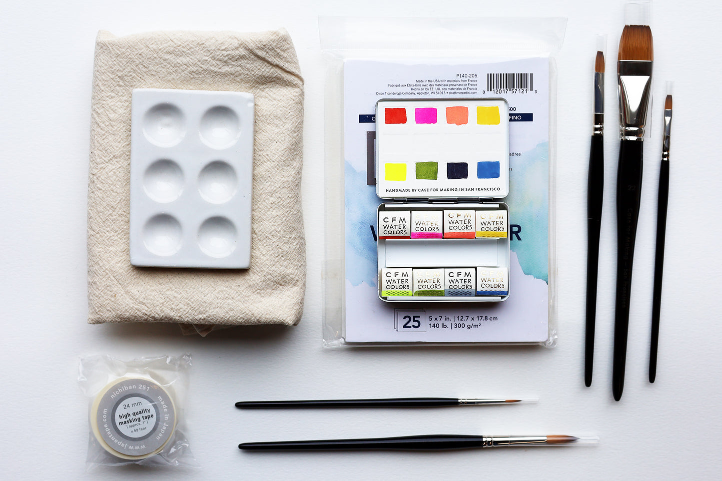 An image of watercolor supplies on a white background including 5 brushes, a watercolor palette, paper, mixing palette, tape and dish cloth.