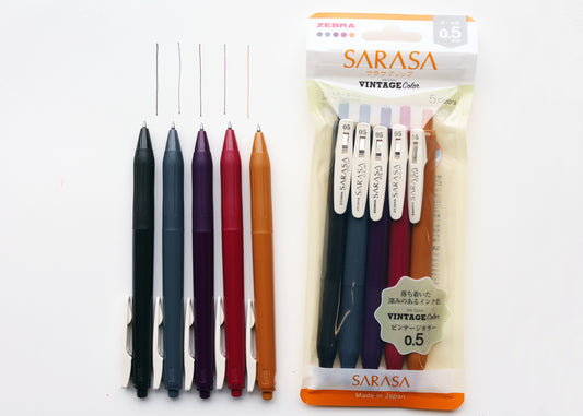Five Sarasa Vintage 0.5 gel pens in assorted colors, shown standing upright next to their retail packaging on a plain white background.