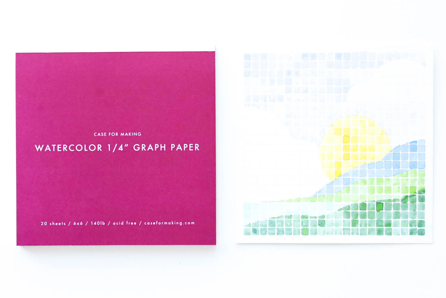 The closed, top-bound 6" x 6" Watercolor 1/4" Graph Paper pad.  Showing the deep fuchsia cover with white lettering.  Also shown is a painted sample sheet of the 1/4" Graph Paper.