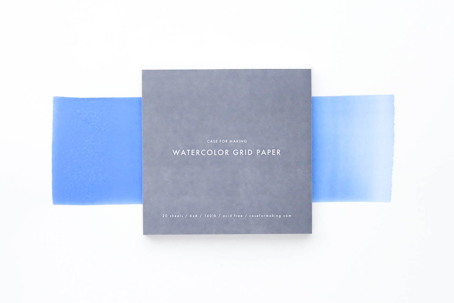 The closed, top-bound 6" x 6" Watercolor Grid Paper pad.  Showing the soft grey cover with white lettering. 