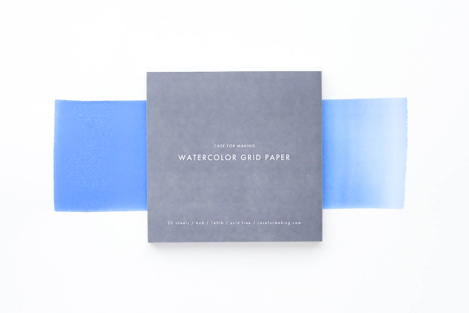 The closed, top-bound 6" x 6" Watercolor Grid Paper pad.  Showing the soft grey cover with white lettering. 